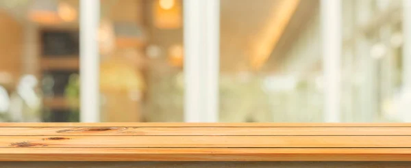 Tablero de madera mesa vacía fondo borroso superior. Mesa de madera marrón perspectiva sobre desenfoque en el fondo de la cafetería. Banner panorámico: se puede usar la maqueta para mostrar o diseñar productos de montaje . — Foto de Stock