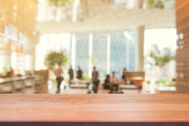 Ahşap tahta boş masa üstü bulanık arkaplan. Kahve dükkanının arka planındaki bulanıklık üzerine perspektif kahverengi ahşap masa - montaj ürünleri görüntüleme veya tasarım anahtar görsel düzeni için kullanılabilir.