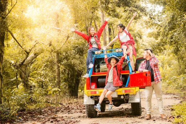 Happy asian young travellers with 4WD drive car off road in forest, young couple looking for directions on the map and another two are enjoying on 4WD drive car. Young mixed race Asian woman and man.