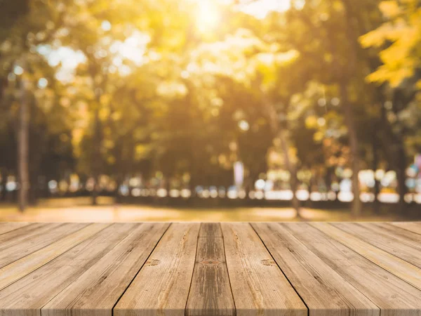 Tablero de madera mesa vacía en frente de fondo borroso. Mesa de madera marrón perspectiva sobre los árboles borrosos en el fondo del bosque - se puede utilizar la maqueta para mostrar o montar sus productos. temporada de otoño . — Foto de Stock