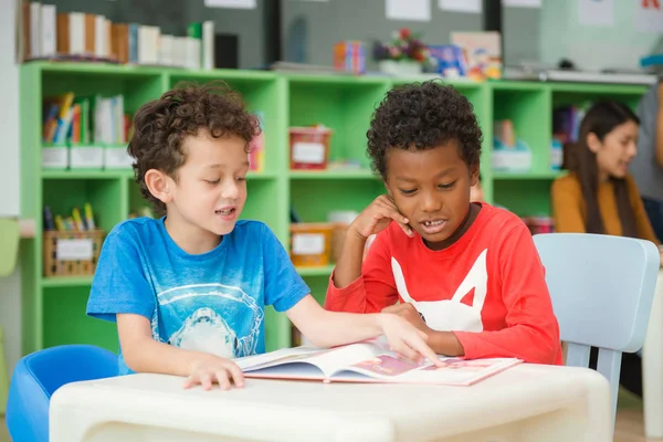 Row of multiethnic elementary students reading book in classroom. Vintage effect style pictures. — Stock Photo, Image