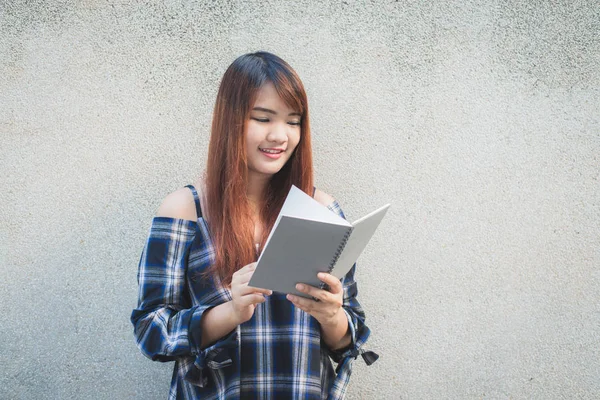 Smiling young beautiful asian women with book. Closeup brown head beautiful young woman pretty happy reading on concrete wall background. Vintage effect style pictures.