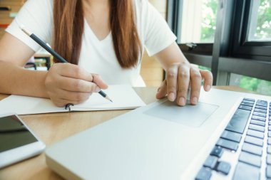 Kız öğrenci Kütüphanesi'nde bir kitaptan not alma. Genç Asyalı kadın kolej kütüphane atamaları yapmak masada oturuyor. Vintage etkisi tarzı resimler.