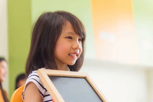 Leuke Aziatische meisje bedrijf leeg schoolbord met blij gezicht in de kleuter klas kleuterschool onderwijs concept, Vintage effect stijl foto 's. — Stockfoto
