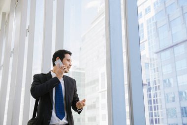 Adam akıllı telefon - havaalanında genç iş adamı. Smartphone ofis binası içinde mutlu gülümseyerek kullanarak rahat kentsel profesyonel iş adamı. Kapalı elbise giyen yakışıklı adam.