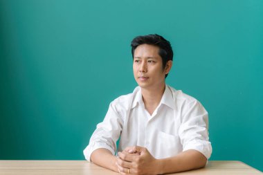 Zevk ile çalışma. Gülümseyen ve onun mavi duvar çalışma evinde otururken gülümseme ile kameraya bakarak Asya işadamı portresi. Vintage filtre uygulanmış görüntü.