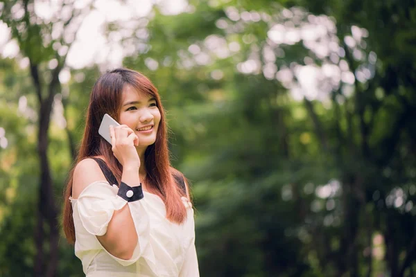 Süße asiatische Frau telefoniert an einem warmen Frühlingstag im Park. — Stockfoto
