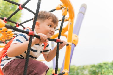 Genç çocuk büyük ağacın altında açık Bahçesi, egzersiz için eliyle siyah ip örgü ve sarı çubuğunda tırmanmak. Vintage etkisi tarzı resimler.