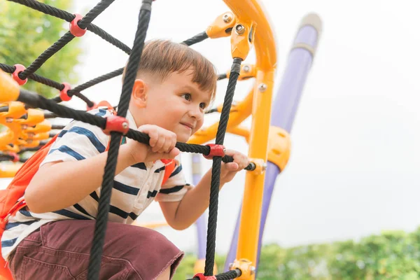 Genç çocuk büyük ağacın altında açık Bahçesi, egzersiz için eliyle siyah ip örgü ve sarı çubuğunda tırmanmak. Vintage etkisi tarzı resimler.
