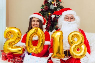 Noel Baba erkek ve kadın için Noel ve yılbaşı ağacı tarafından bir dinlenme sahip hediyeler getirdim. Ev dekorasyon. Balon numaraları 2018 holding.