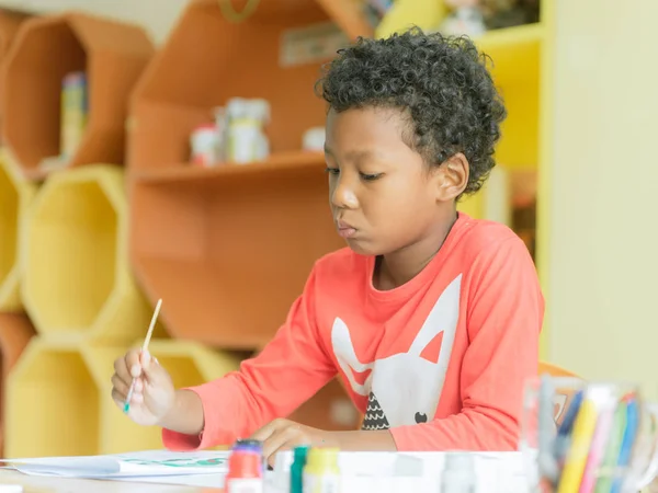 Amerikaans jongen zorg thuis droeg tekening kleur potloden in de kleuter klas, preschool bibliotheek en kind onderwijs concept, Vintage effect stijl foto 's. — Stockfoto