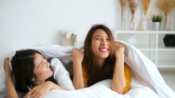 SLOW MOTION - Belle giovani donne asiatiche lesbiche coppia felice che si abbracciano e sorridono mentre si trovano insieme a letto sotto una coperta a casa. Donne divertenti dopo il risveglio. Coppia lesbica insieme al coperto concetto — Video Stock