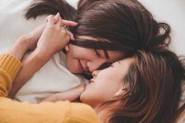 Üstten Görünüm sarılma ve yan yana evde battaniyenin altında yatakta yatarken süre gülümseyen güzel genç Asyalı kadınlar lezbiyen mutlu çift. Komik kadın uyan sonra. Lezbiyen çift birlikte kapalı kavramı.
