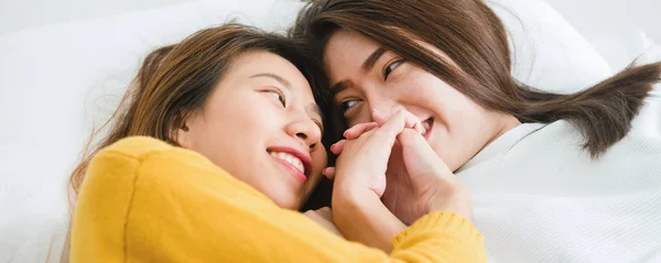 Vue du dessus de belles jeunes femmes asiatiques lesbiennes couple heureux étreignant et souriant tout en étant couché ensemble dans le lit sous couverture à la maison. Des femmes drôles après le réveil. Couple lesbien ensemble concept intérieur . — Photo