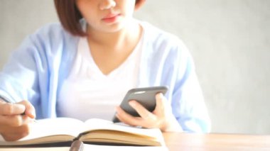İşkadını ahşap masa üzerinde cep telefonu ve yazma rapor kullanın. Asyalı kadın telefonu ve fincan kahve kullanarak. Kahve dükkanında çalışan serbest meslek. Woking office yaşam tarzı dışında.