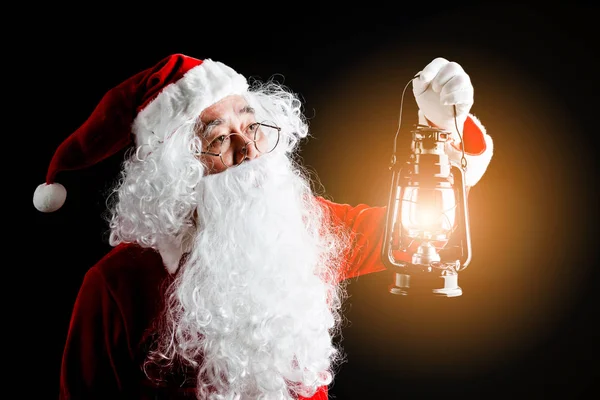 Foto de Papá Noel feliz con una linterna de regalo de Navidad en las manos, aislado sobre fondo negro . —  Fotos de Stock