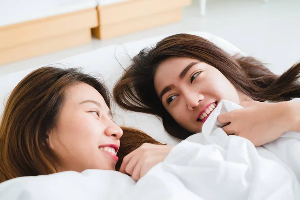 Pandangan atas wanita Asia muda yang cantik pasangan lesbian berpelukan dan tersenyum sambil berbaring bersama di tempat tidur di bawah selimut di rumah. Wanita lucu setelah bangun. Pasangan lesbian bersama di dalam ruangan konsep . — Stok Foto