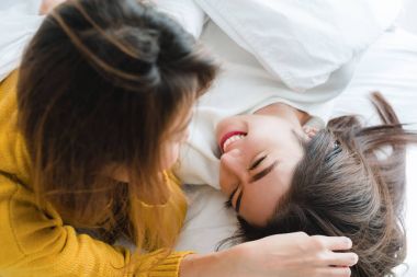 Sarılma ve yan yana evde battaniyenin altında yatakta yatarken süre gülümseyen güzel genç Asyalı kadınlar Lgbt lezbiyen mutlu çift. Komik kadın uyan sonra. LGBT lezbiyen birlikte kapalı çift kavramı.