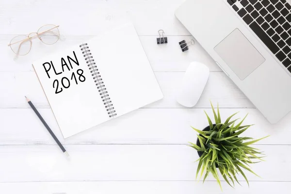 Minimal work space - Creative flat lay photo of workspace desk with Plan 2018 New Year list notebook and laptop on wooden background. Top view flat lay photography. 2018 happy new year concept.