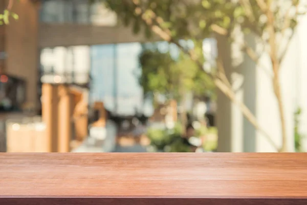 Tablero de madera mesa vacía sobre fondo borroso. Mesa de madera marrón perspectiva sobre desenfoque en el fondo de la cafetería - se puede utilizar la maqueta para la exhibición de productos de montaje o diseño diseño diseño visual clave. — Foto de Stock