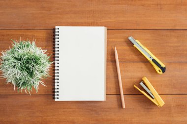 En az çalışma alanı - yaratıcı düz fotoğraf çalışma masası yatıyordu. Defter ve kalem ve bitki açık sahte ile ofis Resepsiyon ahşap masa arka plan. Kopya alanı, düz yatıyordu fotoğraf ile Üstten Görünüm.