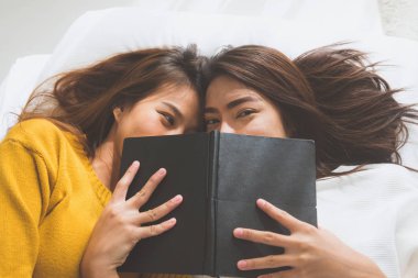 Güzel genç Asyalı kadınlar Lgbt lezbiyen mutlu çift öpücük ve yan yana evinde kitabın altında yatakta yatarken süre gülümseyerek. LGBT uyan sonra komik kadın. LGBT lezbiyen birlikte kapalı çift kavramı.