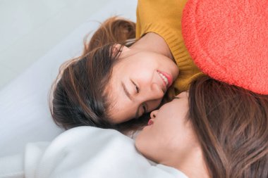 Sarılma ve yan yana evde battaniyenin altında yatakta yatarken süre gülümseyen güzel genç Asyalı kadınlar Lgbt lezbiyen mutlu çift. Komik kadın uyan sonra. LGBT lezbiyen birlikte kapalı çift kavramı.