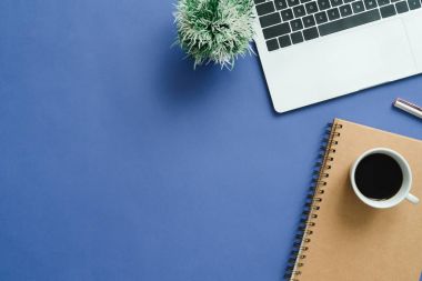 En az çalışma alanı - yaratıcı düz fotoğraf çalışma masası yatıyordu. Üstten Görünüm ofis büro dizüstü bilgisayar, dizüstü bilgisayarlar ve mavi renk arka plan üzerinde kahve fincanı. Kopya alanı, düz yatıyordu fotoğraf ile Üstten Görünüm.