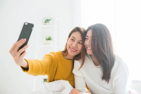 Piękne młode kobiety Azjatki Lgbt szczęśliwa para lesbijek siedzi na łóżku przytul i przy użyciu telefonu biorąc selfie sypialnia razem w domu. LGBT lesbijek para razem pomieszczeniu koncepcja. Spędzać miło czas do domu. — Zdjęcie stockowe