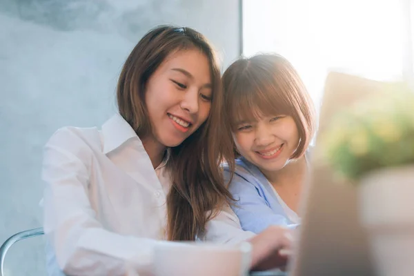 Due giovani donne d'affari sedute a tavola al bar. Donne asiatiche che usano laptop e tazza di caffè. Libero professionista che lavora in una caffetteria. Lavorare fuori ufficio stile di vita. Riunione faccia a faccia . — Foto Stock