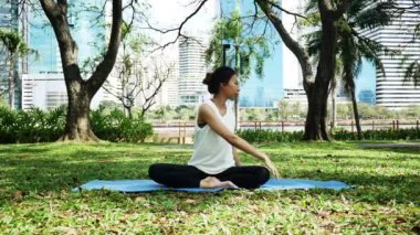 Genç Asyalı kadın yoga açık havada sakin olun ve iç barış keşfetmek için yoga uygulamak ise derin derin düşünür. Yoga ve meditasyon sağlık için iyi faydaları vardır. Yoga spor ve sağlıklı yaşam konsepti.