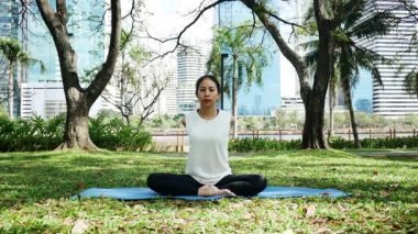 Genç Asyalı kadın yoga açık havada sakin olun ve iç barış keşfetmek için yoga uygulamak ise derin derin düşünür. Yoga ve meditasyon sağlık için iyi faydaları vardır. Yoga spor ve sağlıklı yaşam konsepti.