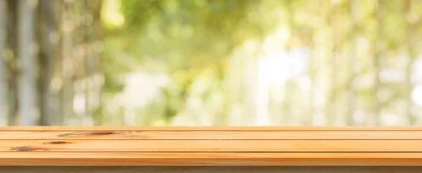 Tablero de madera mesa vacía fondo borroso. Mesa de madera marrón perspectiva sobre los árboles borrosos fondo del bosque - se puede utilizar la maqueta para mostrar o montar sus productos. temporada de primavera. bandera panorámica . — Foto de Stock