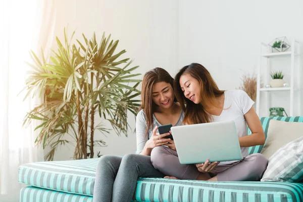 Güzel genç Asyalı kadınlar Lgbt lezbiyen mutlu çift kanepe online satın alma üzerinde oturan evde oturma odasında dizüstü bir bilgisayar ve telefon kullanarak. LGBT lezbiyen birlikte kapalı çift kavramı. — Stok fotoğraf