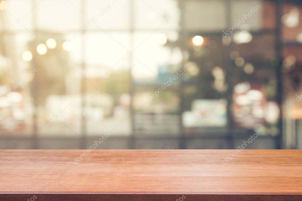 Wooden board empty table top on of blurred background. Perspective brown wood table over blur in coffee shop background - can be used mock up for montage products display or design key visual layout.