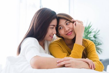 Güzel genç Asyalı kadınlar Lgbt lezbiyen mutlu çift oturan sarılma ve birlikte gülümseyen evde yatak odasında yatak. LGBT lezbiyen birlikte kapalı kavramı çift. Evde güzel vakit.