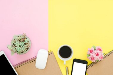 Ofis Masası adlı kullanıcının alanı - düz çalışma boş defter sayfası, kahve fincanı ve sahte telefon tablet pastel arka plan üzerinde yukarı çalışma alanının en iyi görünümü yatırın. Pastel pembe sarı renk arka plan boşluk kavramı.