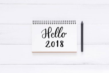 En az çalışma alanı - düz bir defter kalem Beyaz ahşap zemin üzerinde ile dış cephe kaplaması Merhaba tebrik sözcükleri el yazısı Not görünümü fotoğraf yatıyordu. En iyi görünüm düz fotoğraf yatıyordu. Yeni yıl 2018 tebrik kavramı