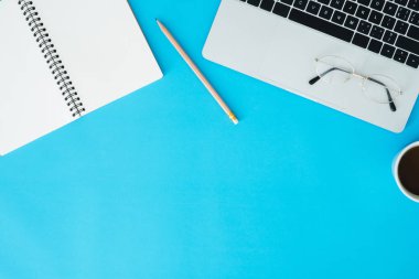 En az çalışma alanı - yaratıcı düz fotoğraf çalışma masası yatıyordu. Üstten Görünüm ofis büro dizüstü bilgisayar, dizüstü bilgisayarlar ve mavi renk arka plan üzerinde kahve fincanı. Kopya alanı, düz yatıyordu fotoğraf ile Üstten Görünüm.