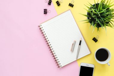 Ofis Masası adlı kullanıcının alanı - düz çalışma beyaz boş defter sayfası, kahve fincanı ve sahte telefon pastel arka plan üzerinde bir çalışma alanının en iyi görünümü yatırın. Pastel pembe sarı renk arka plan boşluk kavramı.