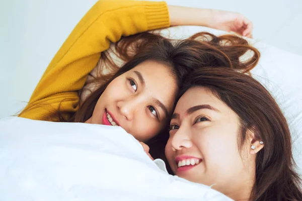 Belles jeunes femmes asiatiques LGBT lesbienne couple heureux montrant surprise et en regardant la caméra tout allongé dans le lit sous la couverture. Des femmes drôles après le réveil. LGBT couple lesbien ensemble à l'intérieur concept — Photo