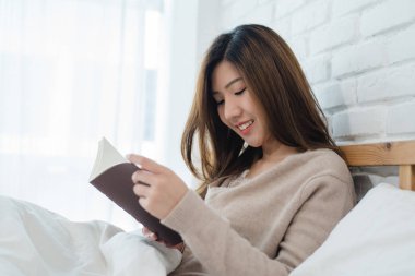Evde rahat giyim kitap zevk okuma yatakta yalan zevk yaşam tarzı mutlu genç Asyalı kadın. Yaşam tarzı kadın kavramı rahatlatıcı.
