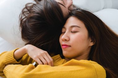 Sarılma ve yan yana evde battaniyenin altında yatakta yatarken süre gülümseyen güzel genç Asyalı kadınlar Lgbt lezbiyen mutlu çift. Komik kadın uyan sonra. LGBT lezbiyen birlikte kapalı çift kavramı.