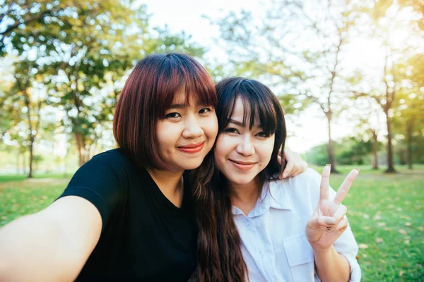 Dwóch przyjaciół piękny szczęśliwy młodych Azjatek, wspólna zabawa w parku i biorąc selfie. Hipster szczęśliwe młode Azjatki uśmiechając się i patrząc na kamery. Pojęcia dotyczące stylu życia i przyjaźni. — Zdjęcie stockowe