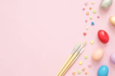 Pembe pastel renkli arka plan üzerinde boya fırçası ile pastel renkler bileşiminde düz yatıyordu üstten görünüm renkli Paskalya yortusu yumurta boyalı. Paskalya günü arka plan üstten görünüm kopya alanı ile.