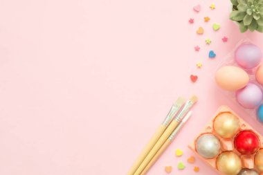 Pembe pastel renkli arka plan üzerinde boya fırçası ile pastel renkler bileşiminde düz yatıyordu üstten görünüm renkli Paskalya yortusu yumurta boyalı. Paskalya günü arka plan üstten görünüm kopya alanı ile.