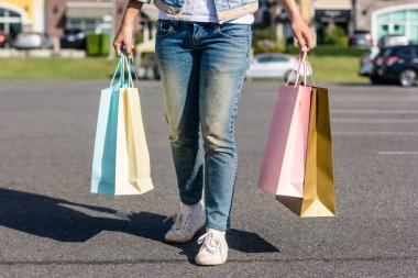 Genç bir Asyalı kadın arka plan pastel bulidings ve mavi gökyüzü ile açık bir bit pazarı alışveriş kapatın. Genç kadın gülümseme ile renkli bir çanta onun elinde. Açık alışveriş kavramı.