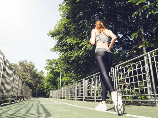 Young asian woman running on sidewalk in morning. Health conscious concept with copy space. Young sport asian woman running upstairs on city stairs. Fitness sport people and healthy lifestyle concept.