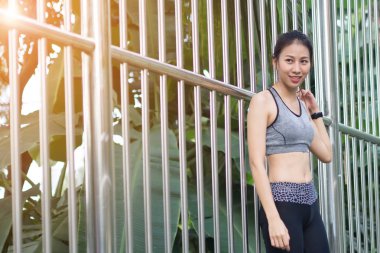 Vücudu tazelemek ve sıcak ışık sabah zevk genç Asyalı kadın egzersiz stand çelik Park karşı koşu sonra rahatlatıcı. Genç kadın sakin execise çalışmasını. Açık egzersiz etkinlik.