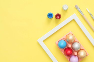 Sarı pastel renk arka plan üzerinde boya fırçası ile pastel renkler bileşiminde düz yatıyordu üstten görünüm renkli Paskalya yortusu yumurta boyalı. Paskalya günü arka plan üstten görünüm kopya alanı ile.